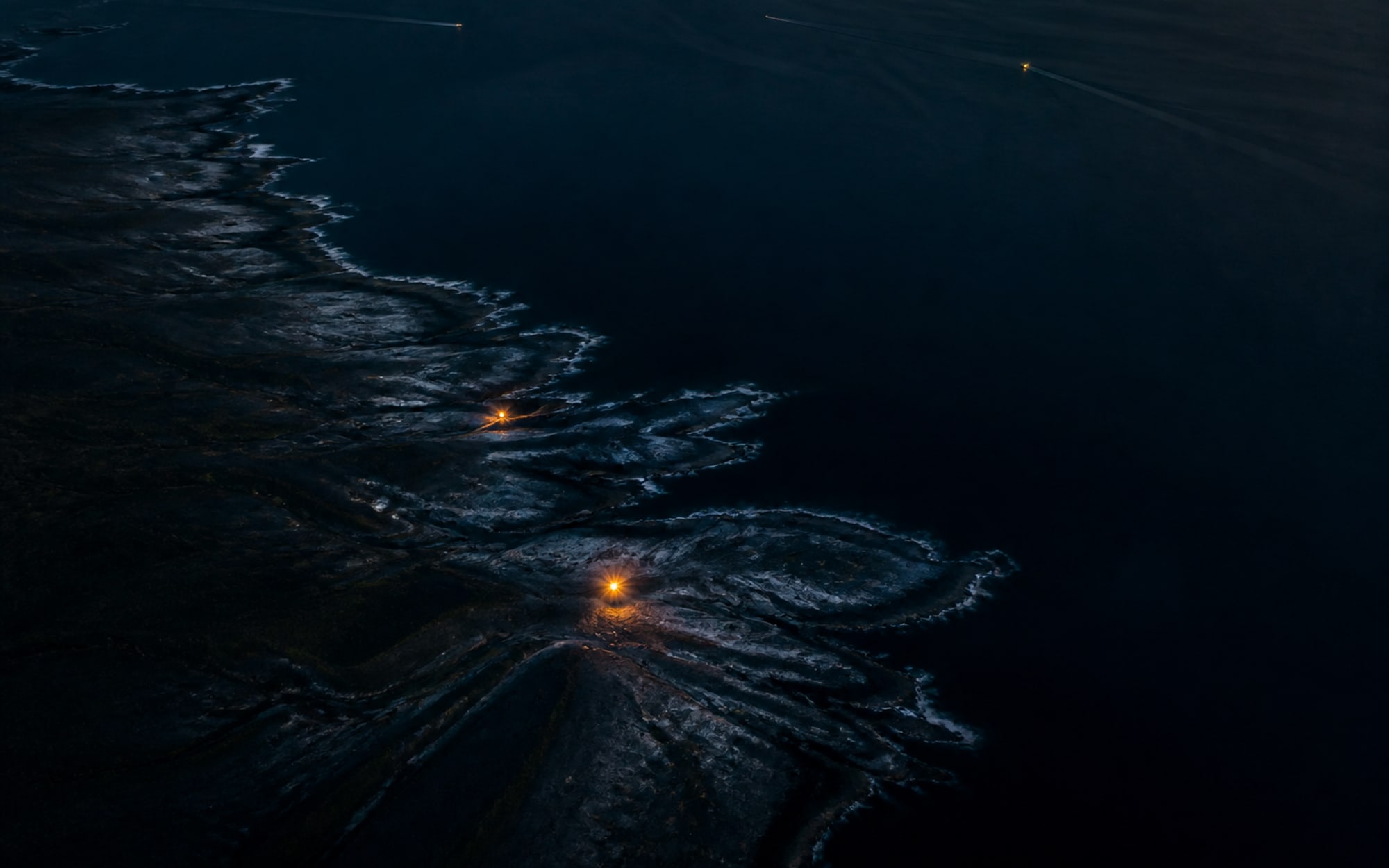 Relief côtier observé de nuit, ponctué de balises de navigation